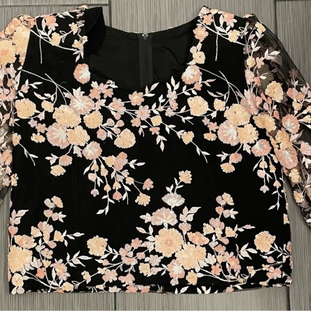 Woman’s black shirt with floral sequins and sheer arms